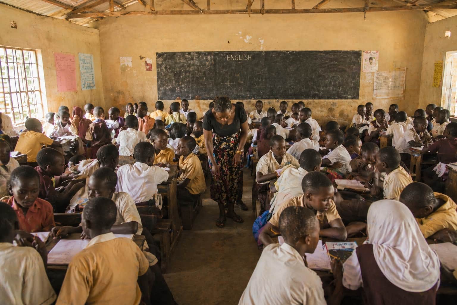 A teacher walking through a busy classroom while students work in pairs