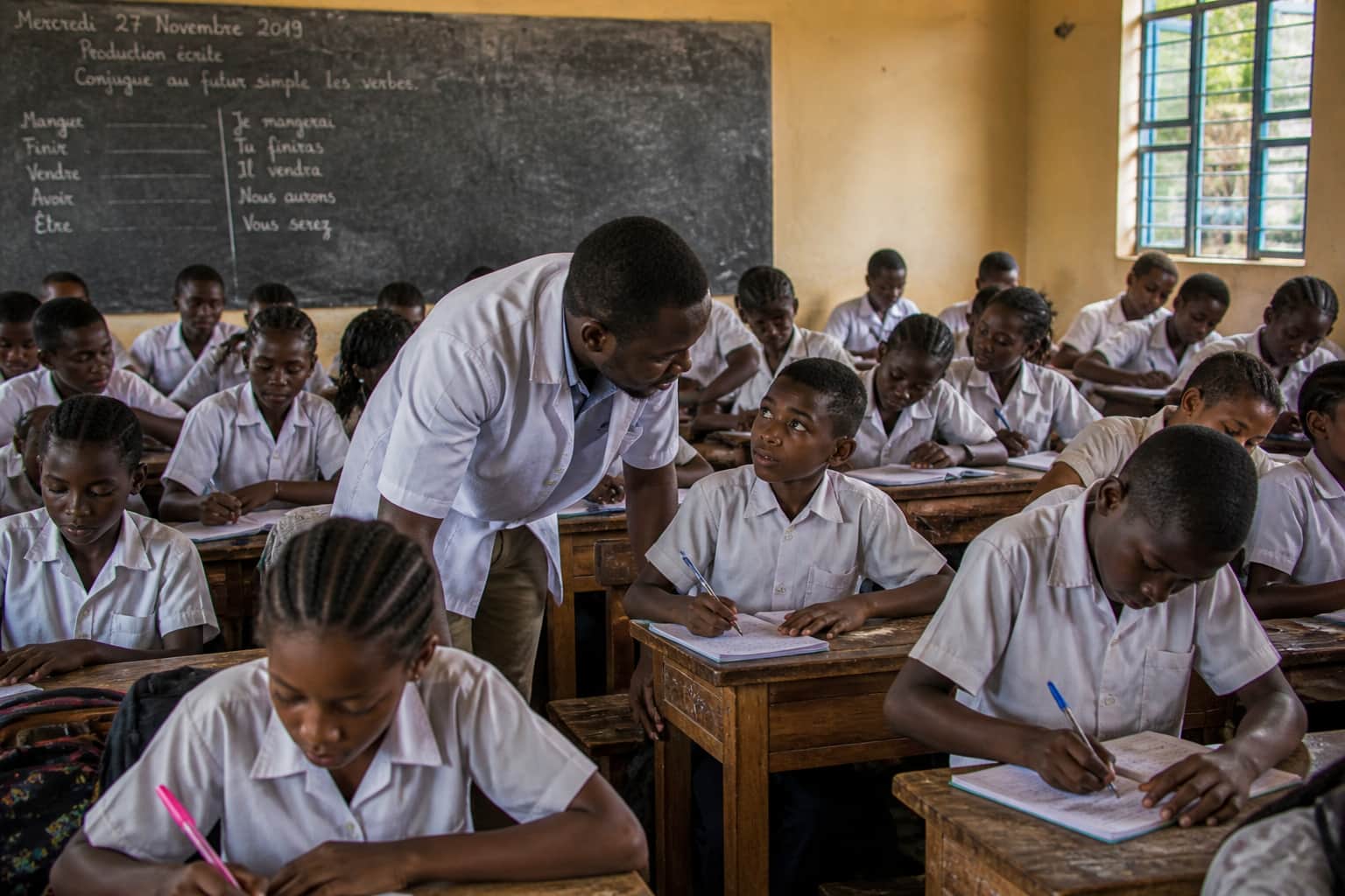 A teacher giving quiet individual help to a student during a class activity